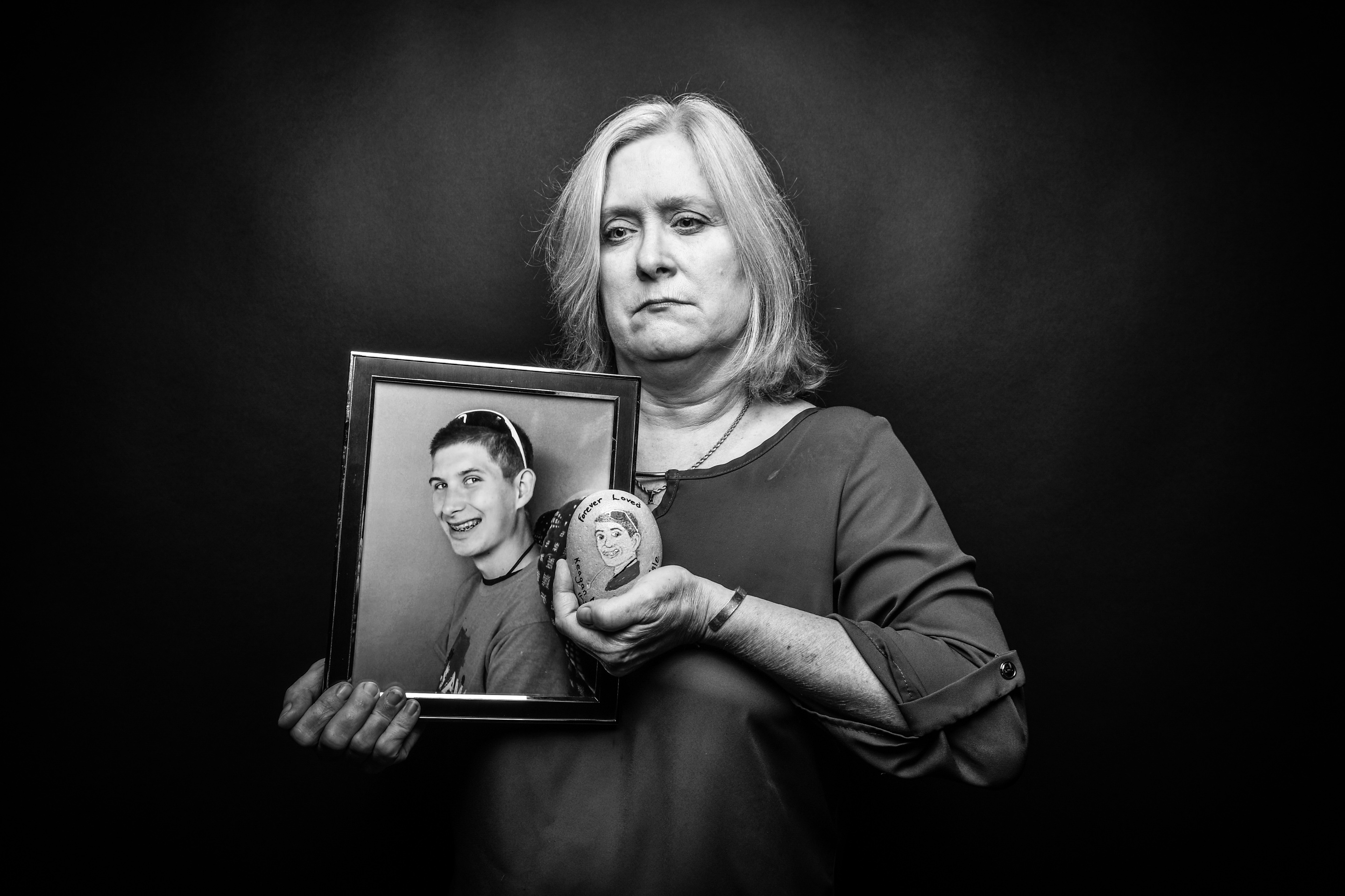 Kim Belle Isle, Davenport, holds a photo of her son Keagan and a rock she painted in his memory. Keagan died by suicide at 17, in 2017.
