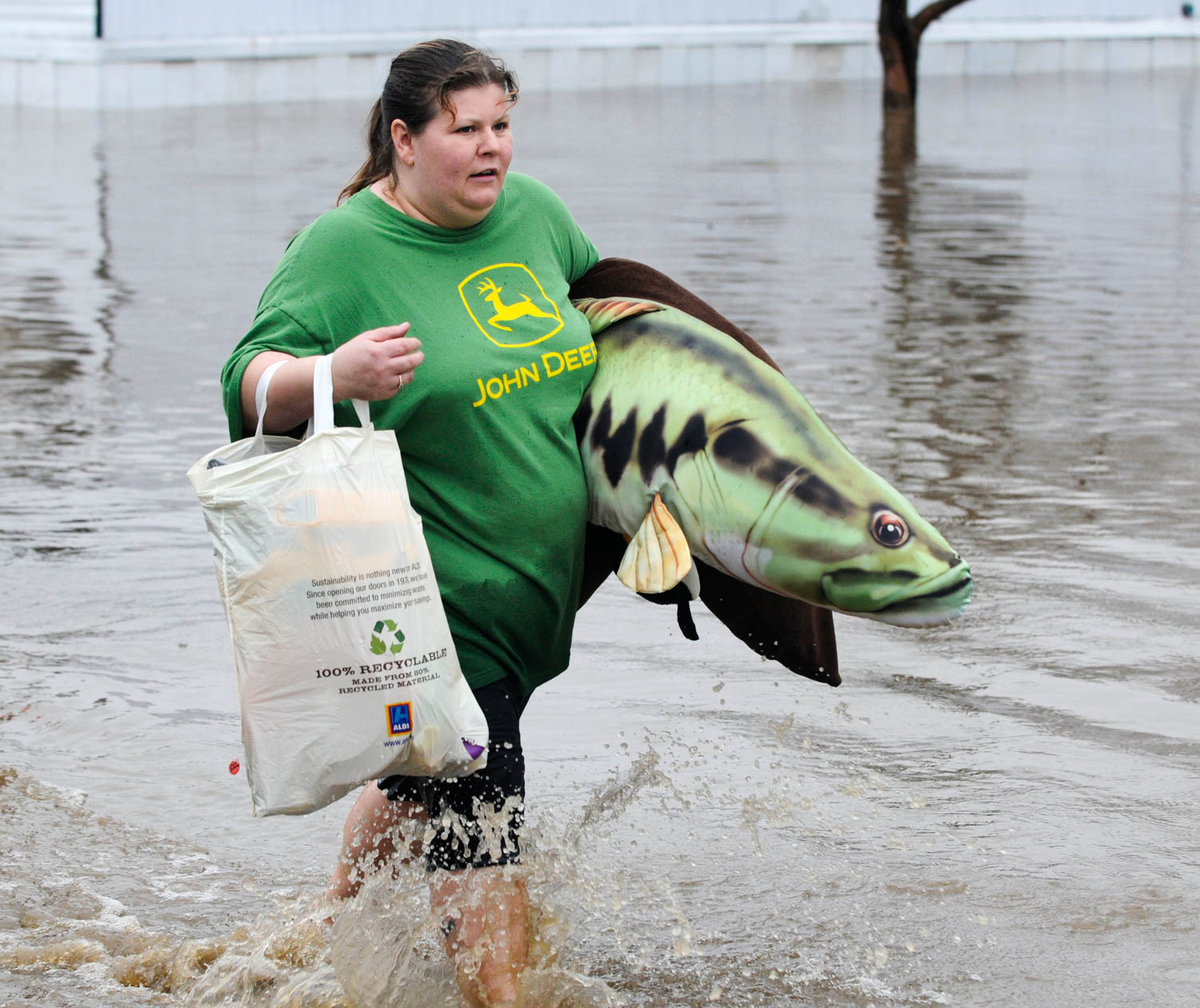 Tracy Svetlick carries family possessions from of her stepson's mobile home in Maple City Mobile Home Park in Geneseo, Ill., Thursday, April 18, 2013, after the Geneseo Creek pushed out of its banks by heavy rain, flooded the park and threatened several businesses. (Todd Mizener - Dispatch/Argus)
